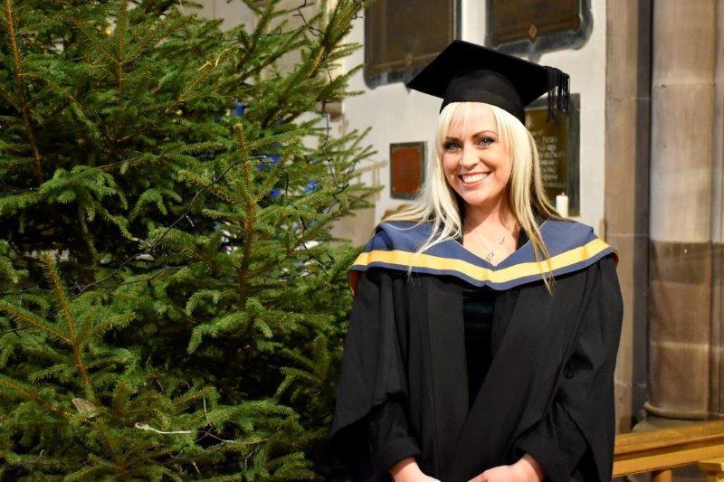 Aimee Baxter posing for a photo by the Christmas tree