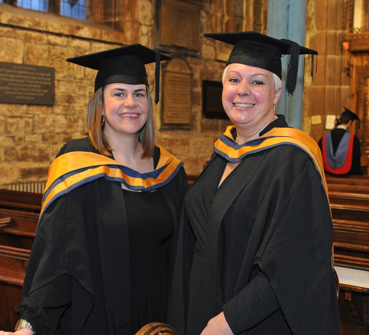 Female students smiling in cap and gowns