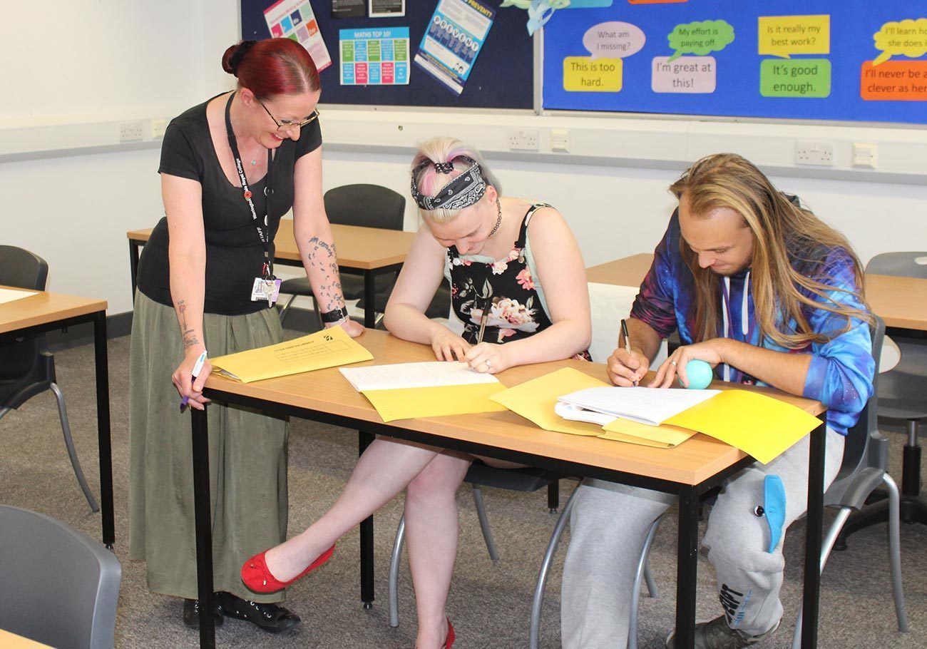 Foundation Learning students sitting at desk with tutor (Foundation Learning thumbnail)