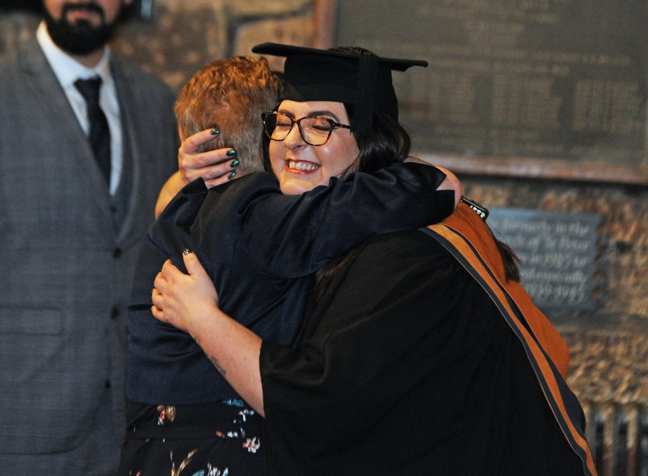 Graduate hugging family member
