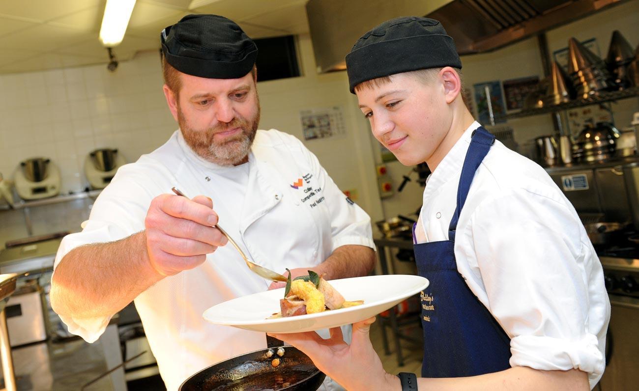 Tutor, Paul, and catering student adding finishing touches to a dish