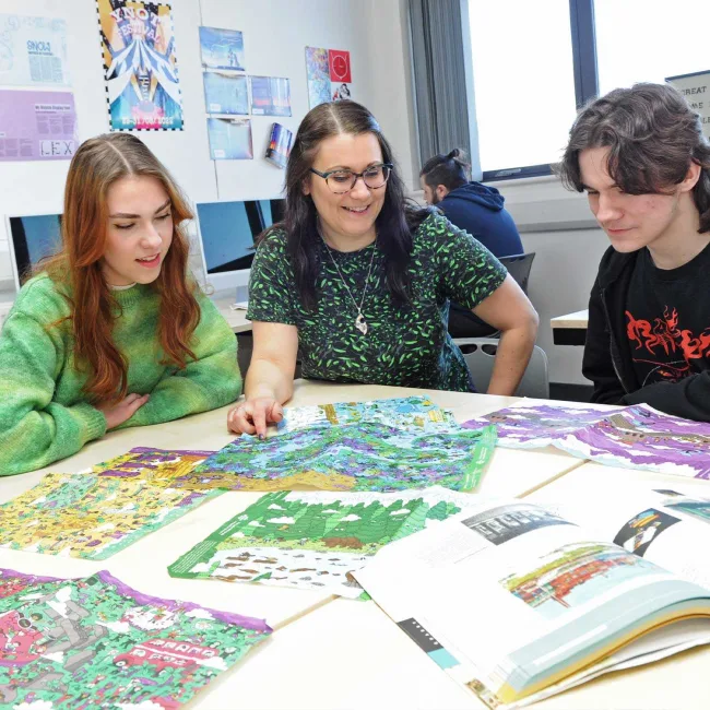 Graphic design students looking at materials with their tutor