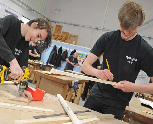 Students drilling wood in carpentry workshop