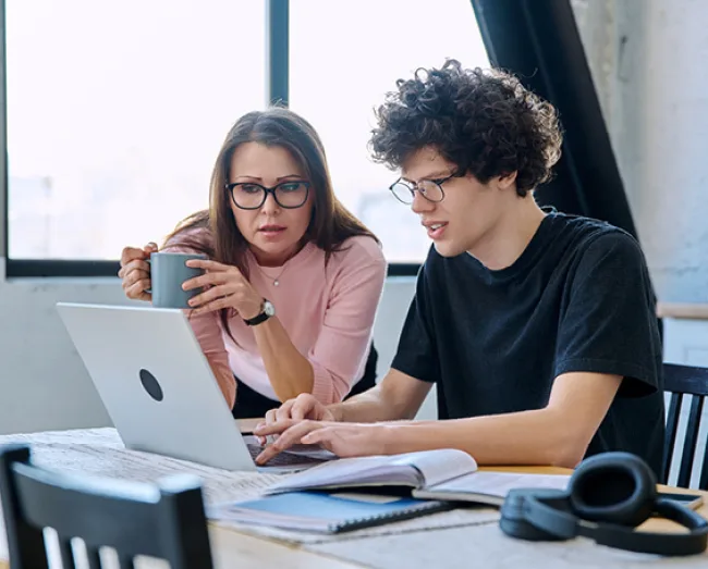Mum and son looking at college options on a laptop